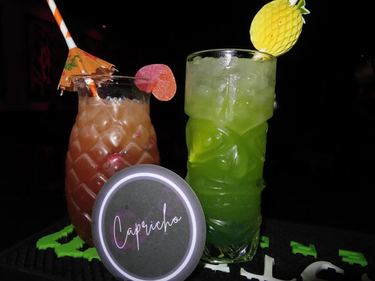 Dos cócteles con sombrillas y fruta sobre un posavasos de Capricho